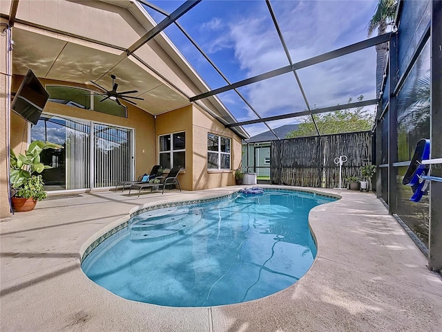 view of swimming pool with glass enclosure, ceiling fan, and a patio area