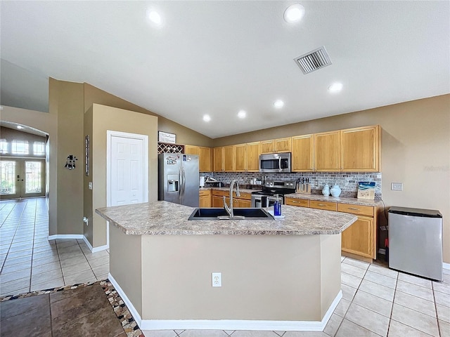 kitchen with sink, a kitchen island with sink, stainless steel appliances, lofted ceiling, and decorative backsplash