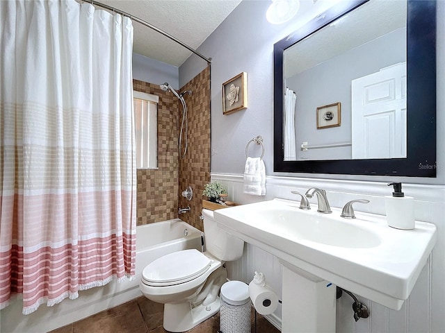 full bathroom featuring sink, tile patterned flooring, a textured ceiling, toilet, and shower / tub combo with curtain