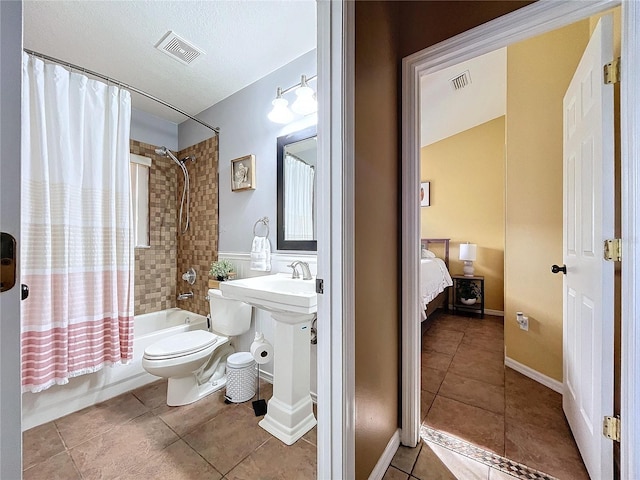 bathroom featuring tile patterned floors, toilet, a textured ceiling, and shower / tub combo