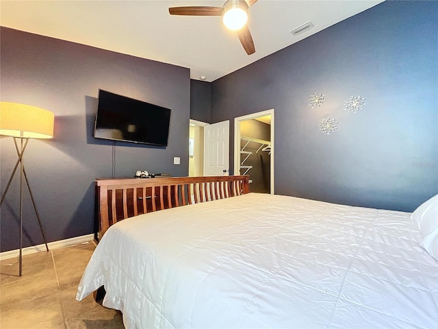 tiled bedroom with a walk in closet, ceiling fan, and a closet