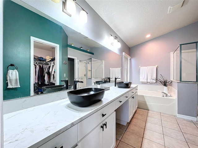 bathroom featuring tile patterned flooring, vanity, independent shower and bath, and a textured ceiling