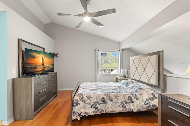 bedroom with a textured ceiling, ceiling fan, light hardwood / wood-style floors, and vaulted ceiling