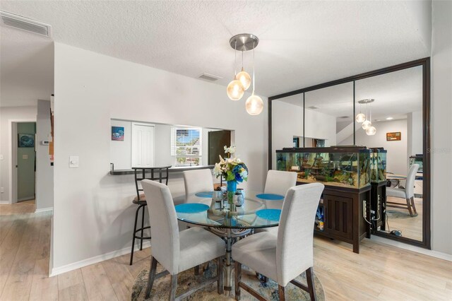 dining space featuring a textured ceiling and light hardwood / wood-style flooring