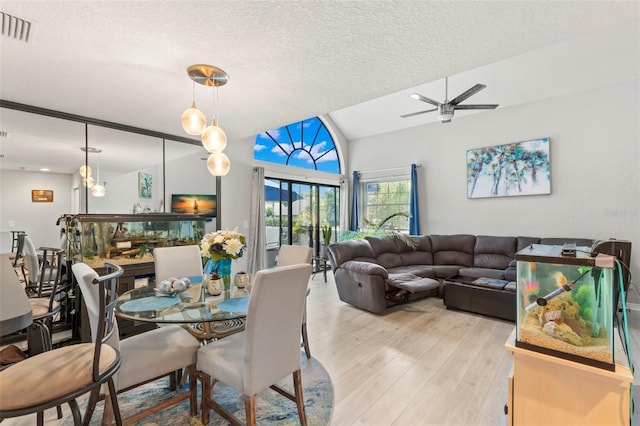 dining area with light wood-type flooring, a textured ceiling, ceiling fan, and lofted ceiling