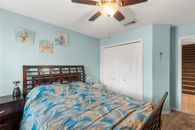 carpeted bedroom with ceiling fan, a textured ceiling, and a closet