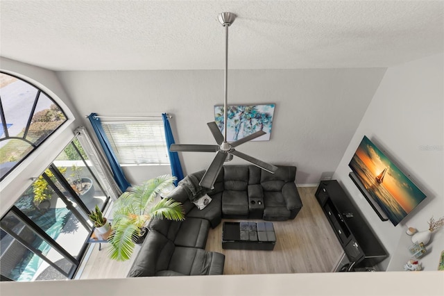 living room featuring lofted ceiling, ceiling fan, a textured ceiling, and hardwood / wood-style flooring