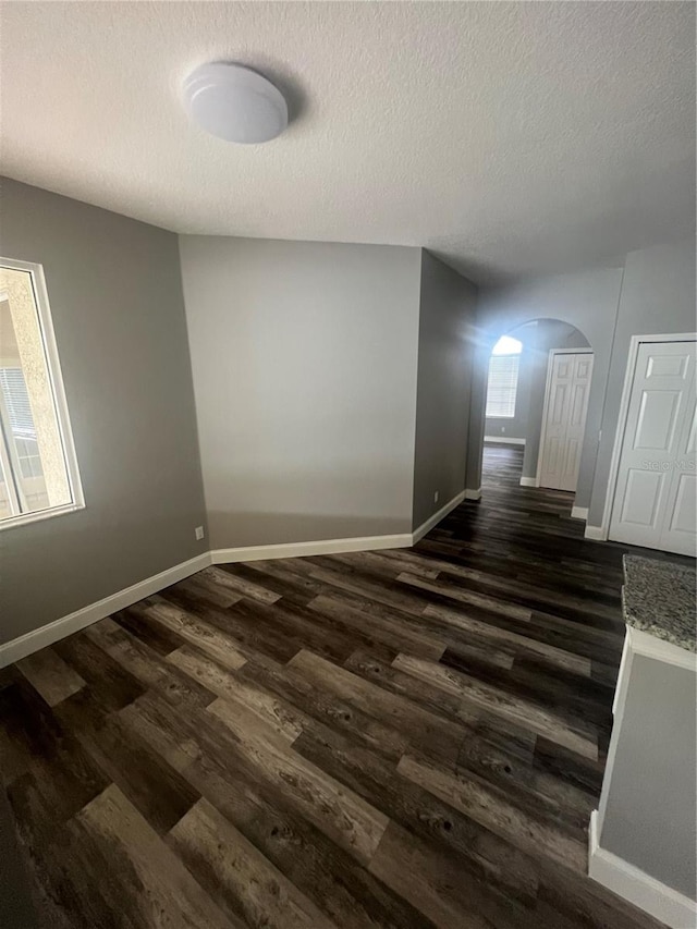 unfurnished room with dark wood-type flooring and a textured ceiling