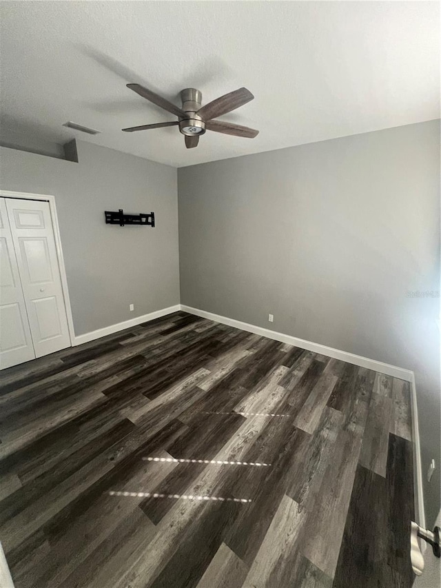 unfurnished bedroom featuring a textured ceiling, dark hardwood / wood-style floors, ceiling fan, and a closet