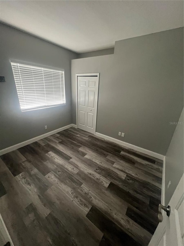 unfurnished bedroom with a closet and dark hardwood / wood-style floors