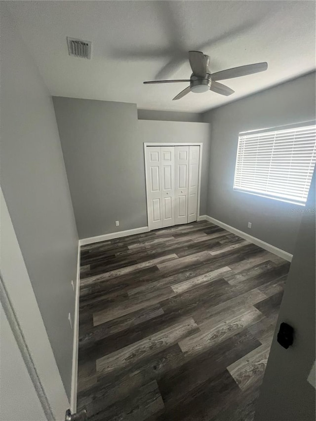 unfurnished bedroom featuring ceiling fan, dark hardwood / wood-style floors, and a closet