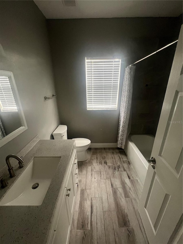 full bathroom with hardwood / wood-style floors, vanity, toilet, and shower / bathtub combination with curtain