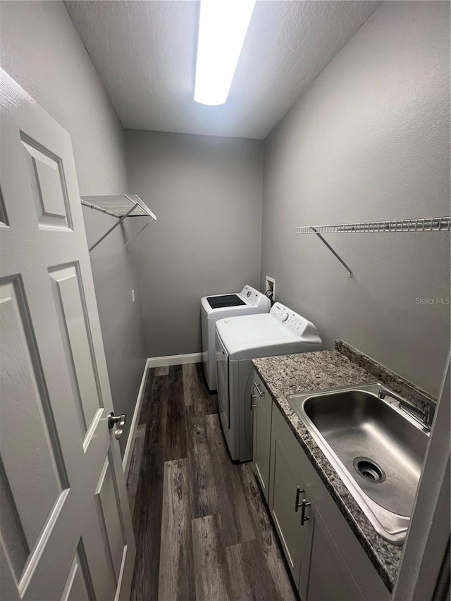 laundry room with a textured ceiling, dark hardwood / wood-style flooring, cabinets, sink, and washing machine and dryer