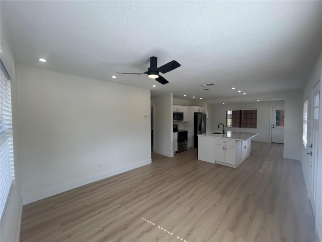 kitchen featuring black range with electric stovetop, refrigerator with ice dispenser, a kitchen island with sink, white cabinets, and light wood-type flooring