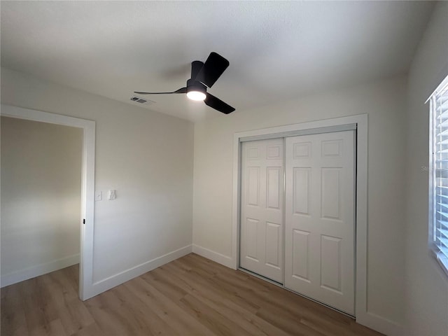 unfurnished bedroom with ceiling fan, light hardwood / wood-style floors, multiple windows, and a closet