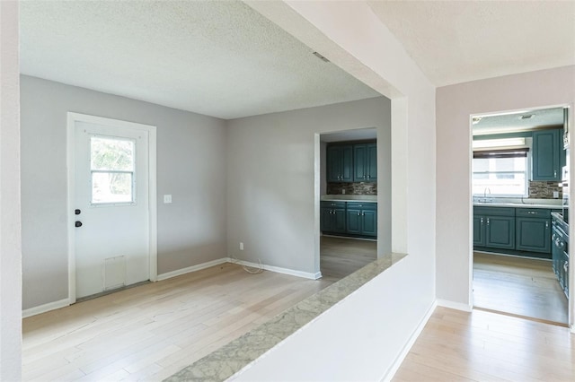 entryway with sink, a textured ceiling, and light wood-type flooring