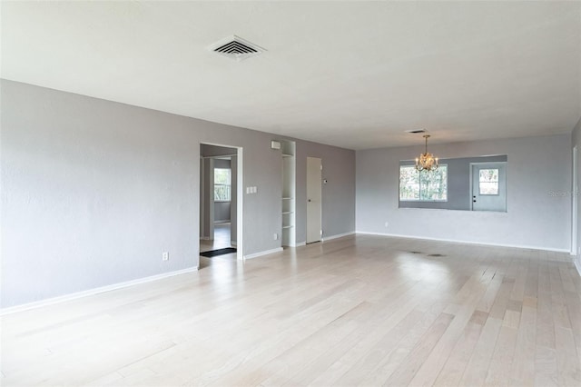 empty room with a chandelier and light hardwood / wood-style flooring