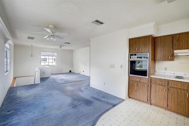 kitchen featuring ceiling fan, oven, a textured ceiling, and ornamental molding