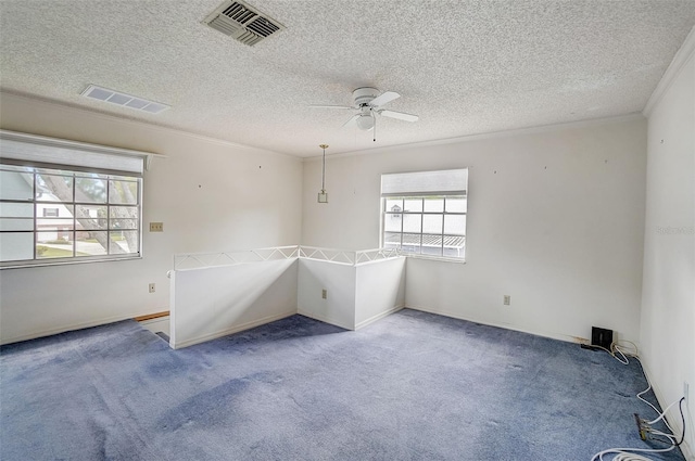 carpeted spare room featuring crown molding, a textured ceiling, and ceiling fan