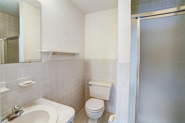 bathroom featuring toilet, a shower with door, tile walls, tile patterned flooring, and a textured ceiling