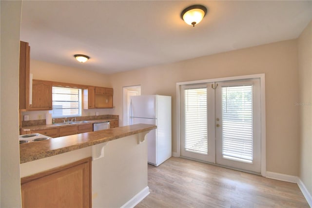 kitchen with white appliances, light hardwood / wood-style floors, a healthy amount of sunlight, and sink