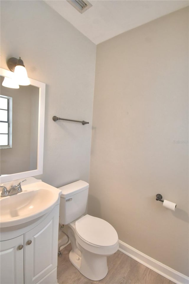 bathroom with hardwood / wood-style floors, vanity, and toilet