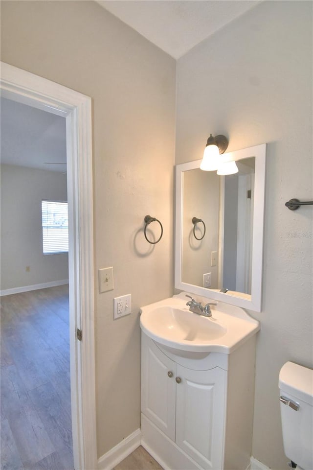 bathroom featuring wood-type flooring, vanity, and toilet