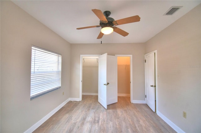 unfurnished bedroom with ceiling fan, light hardwood / wood-style flooring, and a spacious closet