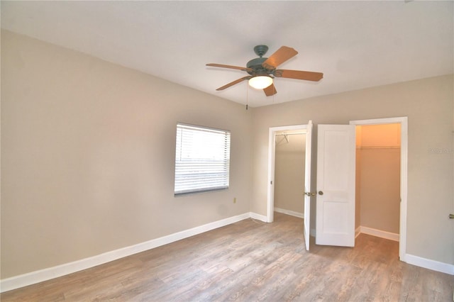 unfurnished bedroom featuring ceiling fan, light hardwood / wood-style floors, a spacious closet, and a closet