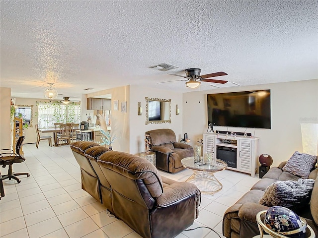 living room with ceiling fan, light tile patterned floors, and a textured ceiling