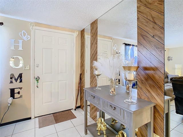 foyer entrance featuring wooden walls, light tile patterned floors, and a textured ceiling