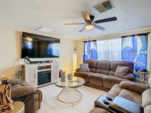 living room with a fireplace, light tile patterned floors, a textured ceiling, and ceiling fan