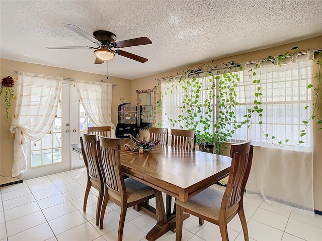 dining space with ceiling fan, light tile patterned flooring, and a textured ceiling