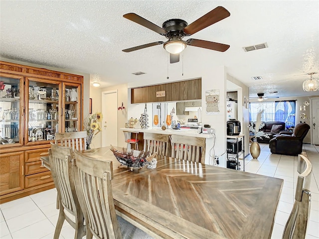 dining area with ceiling fan, light tile patterned floors, and a textured ceiling