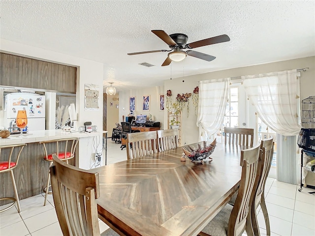 tiled dining room featuring ceiling fan and a textured ceiling