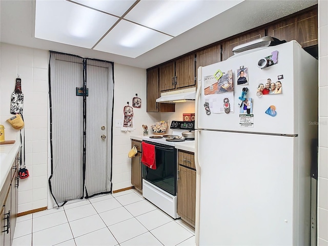 kitchen featuring white appliances, tile walls, and light tile patterned flooring