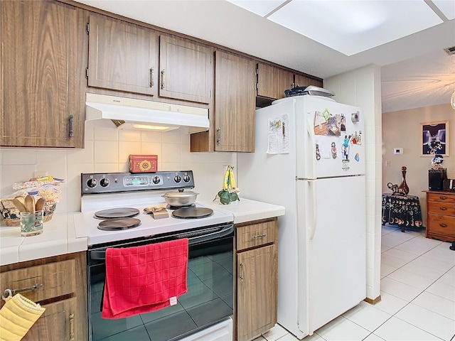 kitchen featuring tasteful backsplash, light tile patterned floors, and white appliances