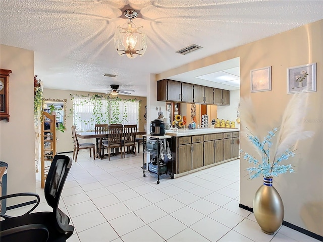 kitchen featuring ceiling fan, light tile patterned flooring, and a textured ceiling