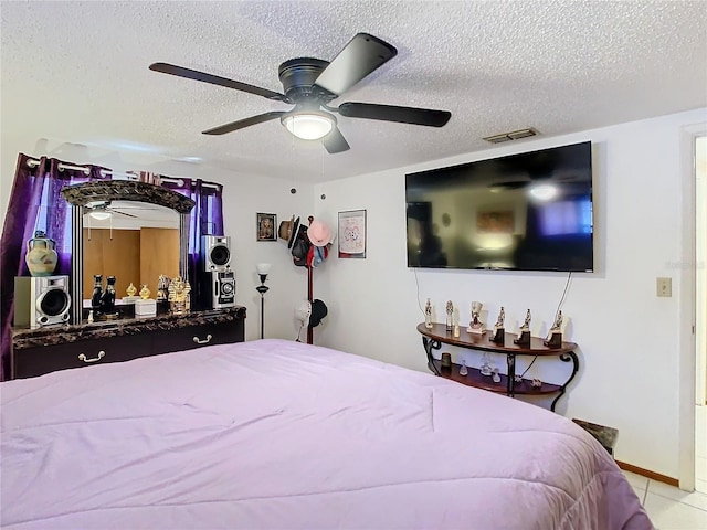 bedroom with ceiling fan, light tile patterned floors, and a textured ceiling