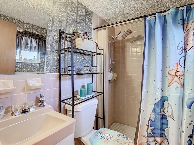 bathroom with curtained shower, sink, a textured ceiling, toilet, and tile walls