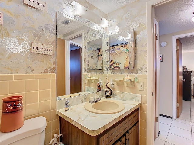 bathroom with toilet, tile walls, tile patterned floors, and a textured ceiling