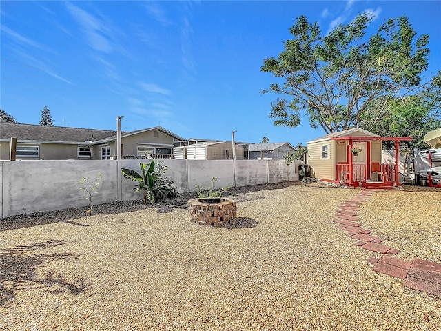 view of yard featuring an outdoor structure and an outdoor fire pit