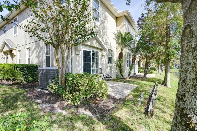 exterior space with central air condition unit, a front lawn, and a patio