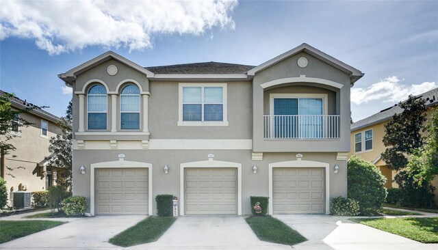 view of property with an attached garage, central AC unit, and stucco siding