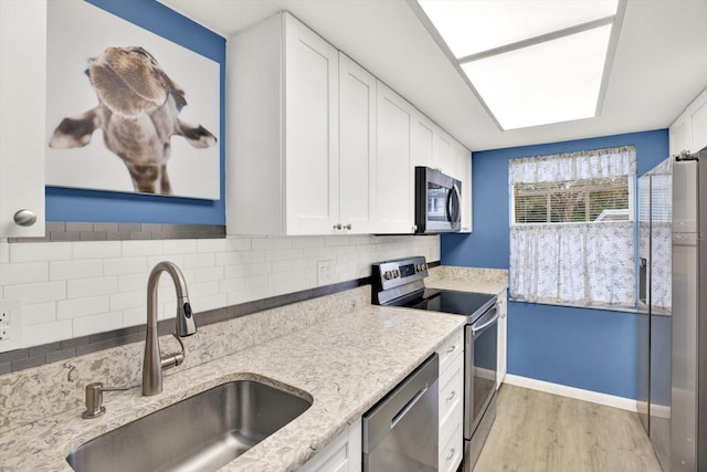 kitchen featuring stainless steel appliances, white cabinets, sink, tasteful backsplash, and light hardwood / wood-style flooring