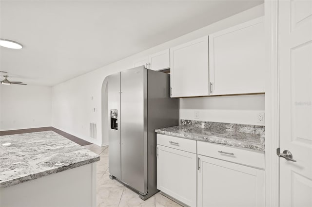 kitchen with white cabinetry, stainless steel refrigerator with ice dispenser, ceiling fan, and light stone counters