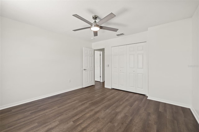 unfurnished bedroom with dark wood-type flooring, ceiling fan, and a closet