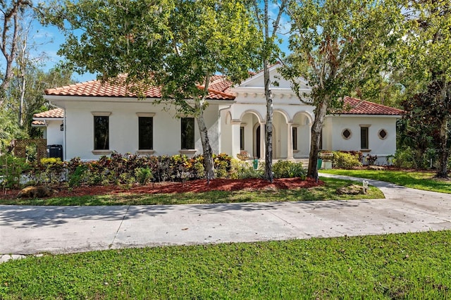 mediterranean / spanish house featuring cooling unit and a front lawn