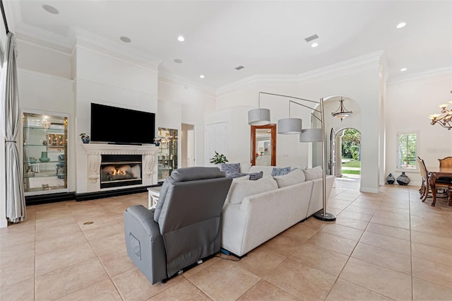 living room with a high end fireplace, ornamental molding, and a towering ceiling