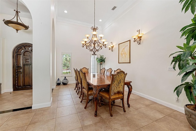 tiled dining area with ornamental molding, a towering ceiling, and a chandelier